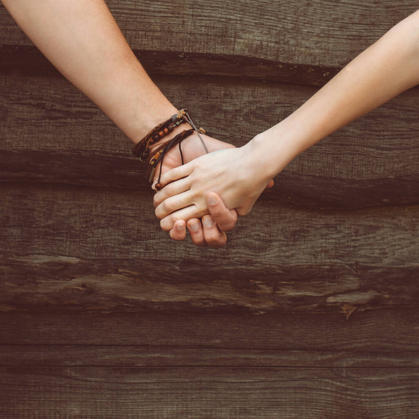 hands of a loving couple on a wooden background - Fotografie, Obrázek