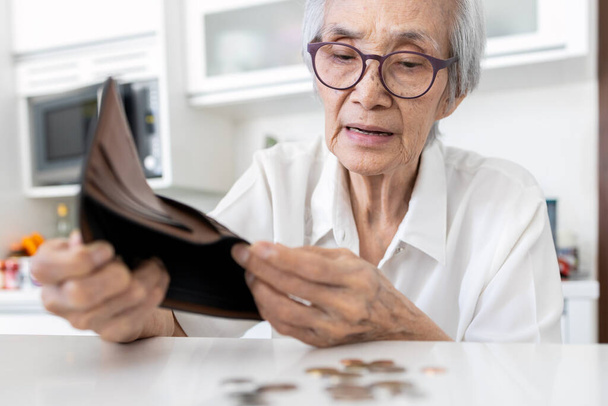 Ενδιαφερόμενη ηλικιωμένη γυναίκα που κρατάει άδειο πορτοφόλι, ηλικιωμένοι που τινάζουν νομίσματα από πορτοφόλι, τελευταία εναπομείναντα νομίσματα, οικονομικά προβλήματα, επενδύσεις, αποταμιεύσεις σχεδιασμού, καθόλου αποταμιεύσεις συνταξιοδότησης, φτώχεια - Φωτογραφία, εικόνα