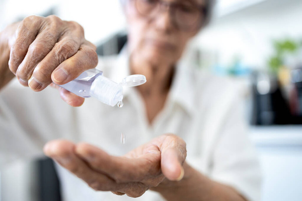Ázsiai idős nő szorítja a kézfertőtlenítő a tenyerébe, vagy öntsük krém palackból, tisztítás, antibakteriális, idős mossa kezet alkoholos fertőtlenítő gél, fertőtlenítése Covid-19, Coronavirus - Fotó, kép