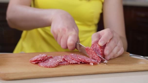 Mulher cozinhar cortes com uma faca pedaços de salsicha de salame em uma tábua de madeira
 - Filmagem, Vídeo