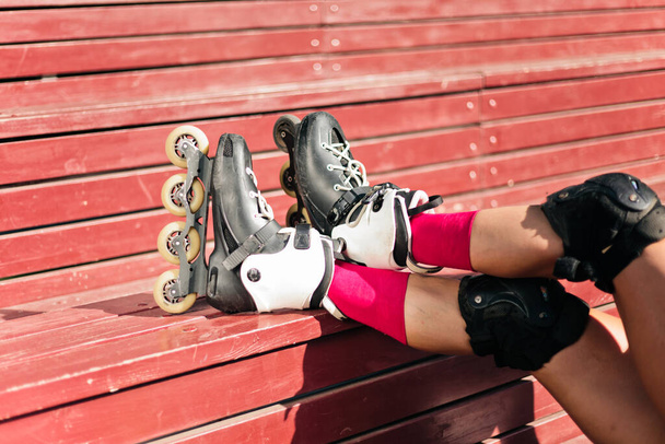 Female legs in roller skates on red wooden boards outdoors Crop photo - Foto, Bild