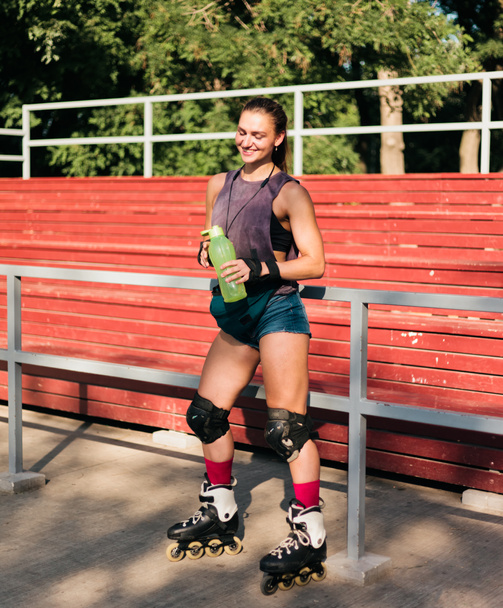 Femme gaie en vêtements de sport et patins à roulettes posant au skate park. Le concept des activités de plein air. Hobby. Style de vie sportif
 - Photo, image