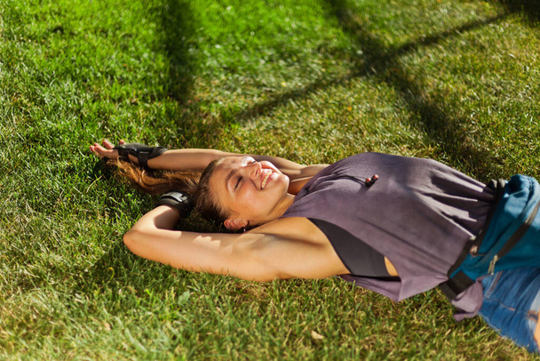 Young cheerful sport woman resting lying on the lawn grass in the park - Photo, Image