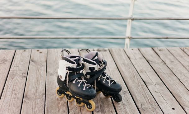 Old roller skates on a beach terrace against the sea - Photo, Image