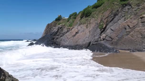 Dalgalar kayalara çarpıyor ve güneşli bir yaz gününde öğlen vakti Bakio sahilinde köpük üretiyor. - Video, Çekim