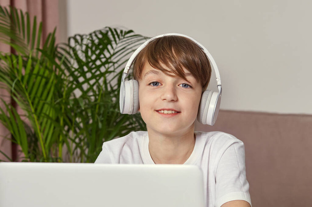A smiling boy in headphones is watching a movie. Looks at the camera. - Foto, Bild