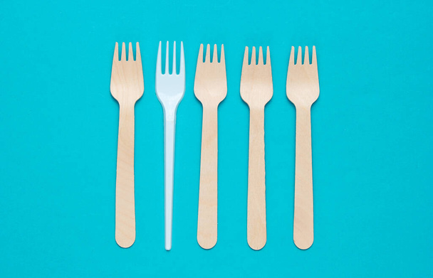 Minimalistisch milieuconcept. Houten en plastic vorken op een roze blauwe achtergrond. Creatieve eco-achtergrond. Bovenaanzicht - Foto, afbeelding