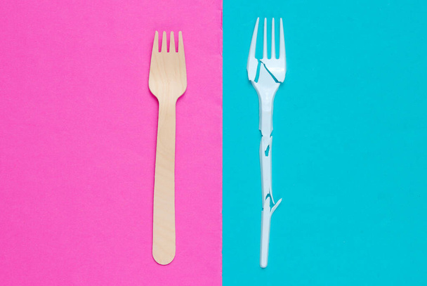 Minimalistisch ecologisch schoon stilleven. Pop Art. Gebroken plastic vork en houten vork op blauwe roze ondergrond. Bestek gemaakt van natuurlijke materialen, Bovenaanzicht - Foto, afbeelding