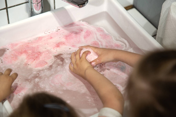 Гигиена и уход, дети моют руки в раковине. Защита от ковинда-2019 коронавируса с использованием средств личной гигиены и антибактериального мыла. Уход за здоровьем детей и семей
. - Фото, изображение