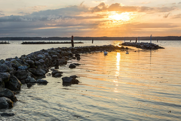 美しい夕日の間にバルト海の防波堤の岩  - 写真・画像