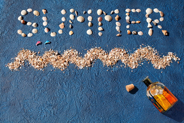 Word καλοκαίρι από κοχύλια, κύμα της θάλασσας, χρυσή άμμο, άλμα δελφίνια, χρωματιστό γυάλινο μπουκάλι με φελλό σε μπλε φόντο top view close up, έννοια καλοκαιρινές διακοπές, θάλασσα παραλία σχεδιασμό διακοπών, αντίγραφο χώρου - Φωτογραφία, εικόνα