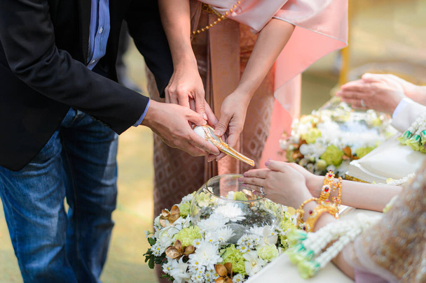 Weihwasser übergießt Braut und Bräutigam mit Händen, traditionelle thailändische Hochzeitsverlobung - Foto, Bild