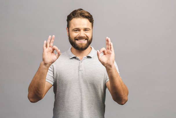 A handsome man in casual shirt isolated on grey background showing ok sign. - Photo, Image