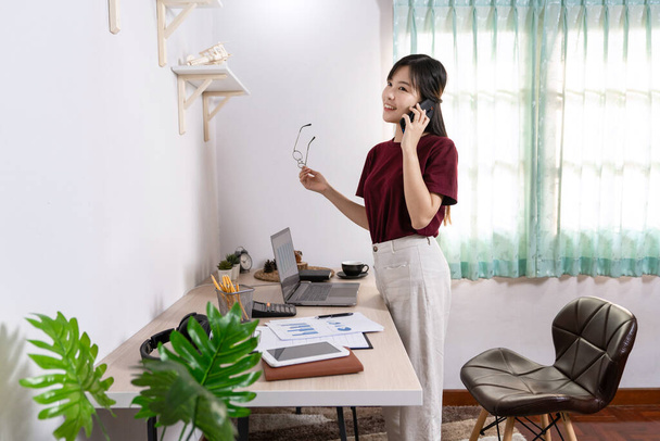 Houkutteleva nuori kaunis aasialainen nainen Yrittäjä tai freelancer työskentelee kotona kannettavan tietokoneen liiketoimintaraportteja ja online-viestintää olohuoneessa sohva, työskentelevät etäyhteyden käsite - Valokuva, kuva