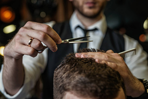 Barbers hands cut hair with scissors, closeup, classic clothes, tie and shirt - Fotó, kép