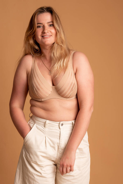 Beautiful overweight woman in beige swimsuit on pink background - Foto, Bild