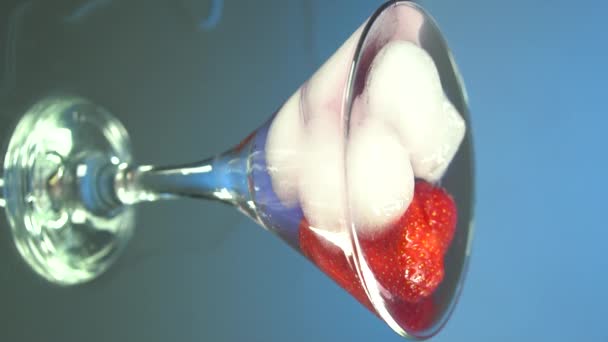 Makro eines professionellen Barkeepers ist das Einfüllen professioneller Kristalleiswürfel in ein Glas, während er seinen Kunden in der Bar oder Diskothek einen alkoholischen Cocktail zubereitet. Vertikales Video für Smartphones und Tablets - Filmmaterial, Video