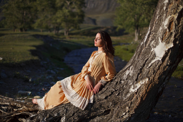 ragazza in abito vintage cammina su uno sfondo di montagne al tramonto
 - Foto, immagini