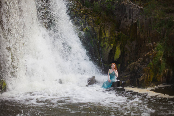 piękna rudowłosa dziewczyna kąpie się w burzliwym strumieniu wodospadu, gorące lato - Zdjęcie, obraz