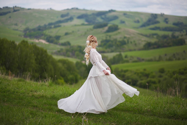 la novia camina en el campo contra el telón de fondo de las montañas, una sesión de fotos en Altai, un retrato de la novia, una chica en un vestido blanco al estilo del boho
 - Foto, imagen