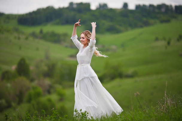panna młoda spaceruje w polu na tle gór, sesja zdjęciowa w Altai, portret panny młodej, dziewczyna w białej sukience w stylu boho - Zdjęcie, obraz