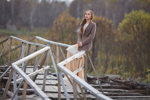 Eski moda elbiseli kız köprüde duruyor. - Fotoğraf, Görsel