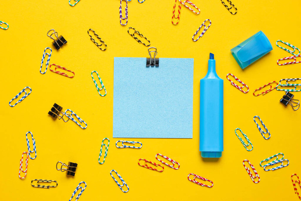 Канцелярське приладдя. Паперова застібка, ручка з фетру, шматок паперу на жовтому тлі
 - Фото, зображення
