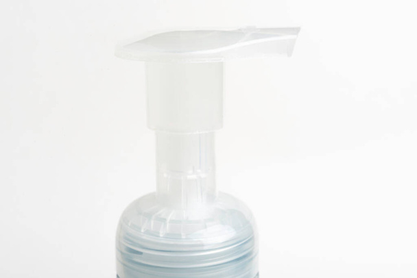 Una imagen de cerca de la bomba superior translúcida de un dispensador de botellas de plástico de jabón de espuma sobre un fondo blanco
. - Foto, Imagen