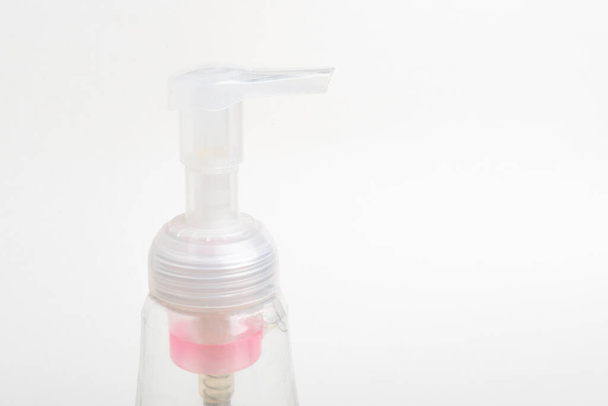 Uma imagem de close-up da bomba superior translúcida de um dispensador de garrafa de plástico de sabão de espuma em um fundo branco
. - Foto, Imagem