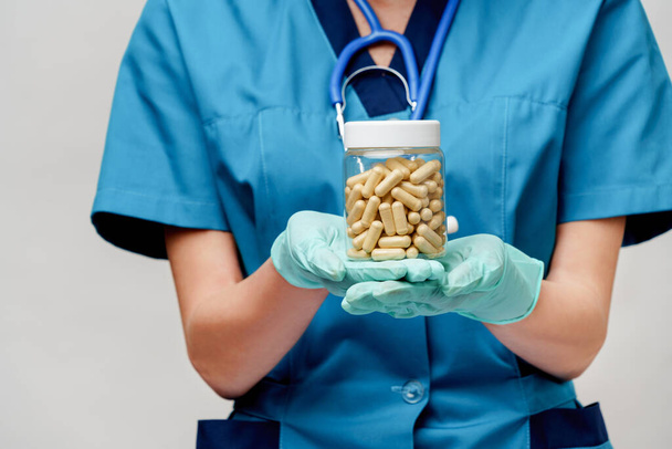 medical doctor nurse woman wearing protective mask and rubber or latex gloves - holding pills - Foto, Imagen