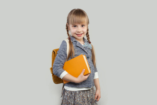 Joyeux sourire enfant fille avec sac d'école et livre. Concept de retour à l'école
 - Photo, image