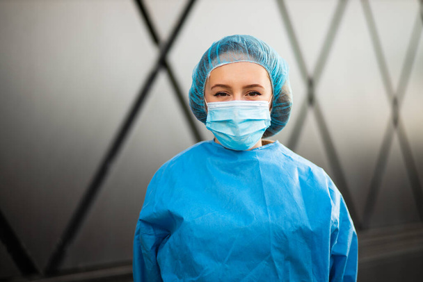 Πορτρέτο της γυναίκας γιατρό ή νοσοκόμα σε ιατρική μάσκα και χειρουργικό καπέλο κοιτάζοντας σας - Φωτογραφία, εικόνα