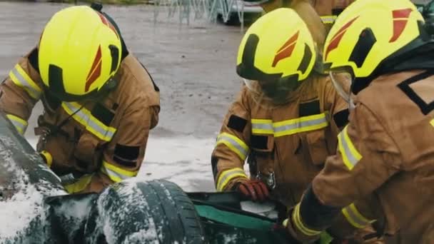 チームオフ消防士は事故に巻き込まれた人を救うためにオープンカーのドアを切ろうとしています。スローモーション - 映像、動画