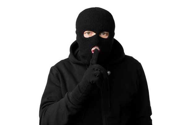 Retrato de ladrón en pasamontañas negro sosteniendo los dedos en el labio
 - Foto, imagen