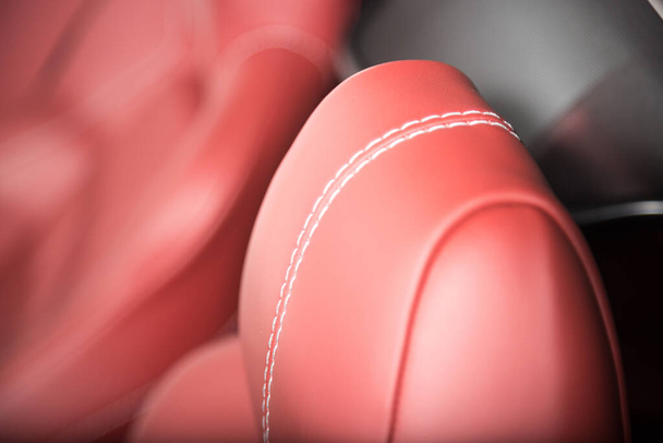 Detailfoto van een rode lederen hoofdsteun op een autostoel - Foto, afbeelding
