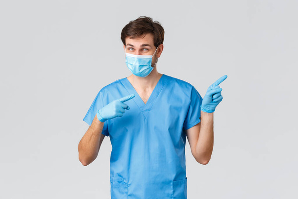 Covid-19 、医療従事者と病院のコンセプト。医療用マスク、手袋、青の看護師や外科医の頭蓋骨の熱狂的な医師は、右の指を指して、方法を示し、広告を促進 - 写真・画像
