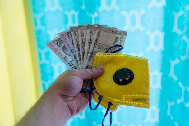 Раздача индийских банкнот, желтой маски и дезинфицирующего средства, на красочном фоне
 - Фото, изображение