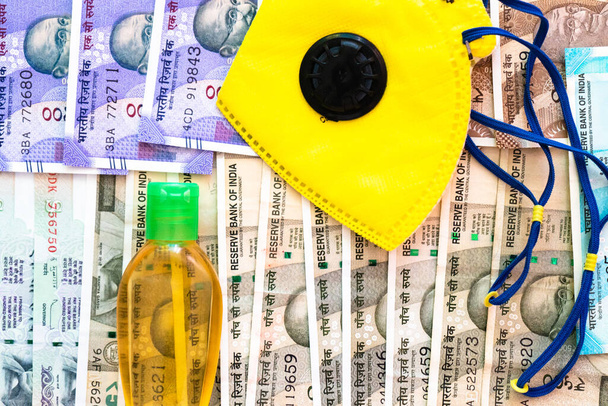 Sécurité et affaires essentielles masque jaune et désinfectant placés sur le lit de monnaie indienne
 - Photo, image
