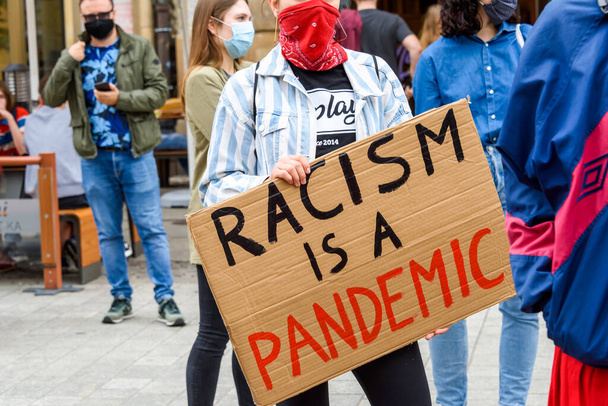 Wroclaw, Poland, 06.06.2020 - Young people hold a poster with words "Racism is a pandemic" on polish peaceful protest against racism and hatred in Wroclaw city. - Fotó, kép