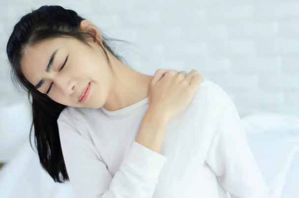 Las mujeres asiáticas usan pijamas blancos en el dormitorio. Tiene dolor en la zona del cuello.
. - Foto, imagen