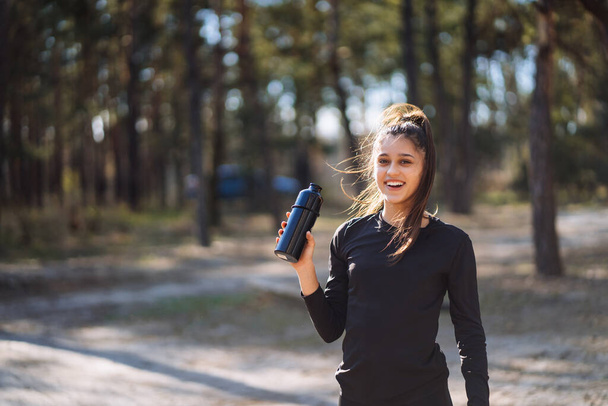 Sottile giovane donna che beve acqua dopo l'allenamento - Foto, immagini
