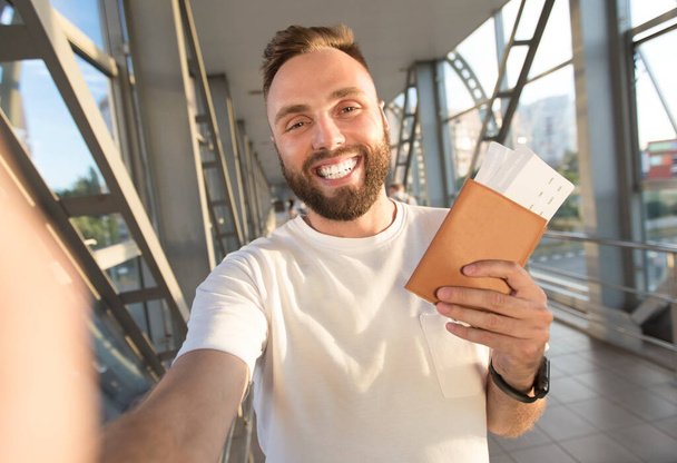 Hombre feliz tomando selfie en el aeropuerto, esperando el embarque
 - Foto, Imagen