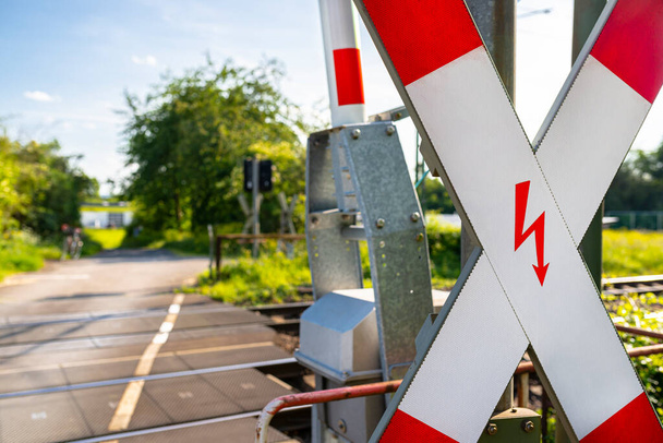 Hlídané železniční přejezd na venkově s otevřenými bariérami a kříž svatého Ondřeje. - Fotografie, Obrázek