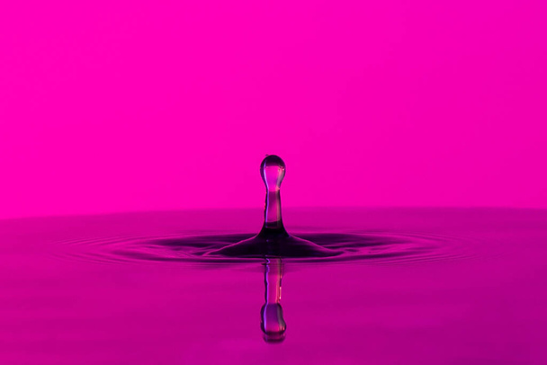 Sessiz bir zemin üzerine renk arkaplanı üzerine bir damla sıvı sıçraması - Fotoğraf, Görsel