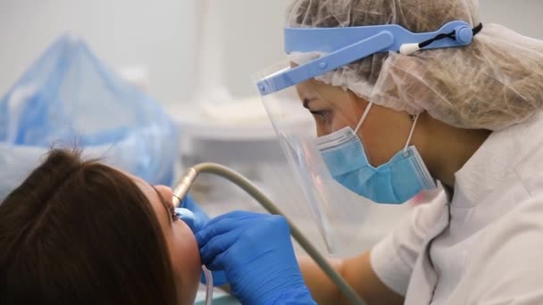 Closeup of young dentist in protective mask and glasses curing tooth cavity. - Filmagem, Vídeo