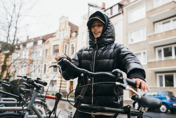 Junge Frau holt ihr Fahrrad vom Parkplatz - Foto, Bild
