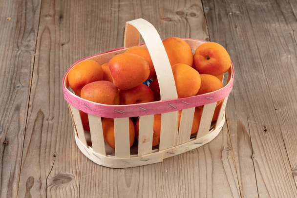 Wooden basket of ripe apricots on a wooden table - Foto, immagini