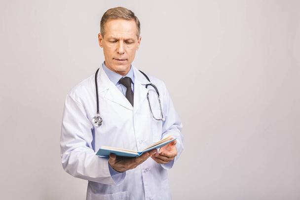 Senior doctor reading a book isolated over grey background. - Foto, Bild