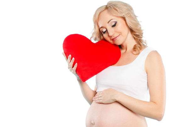 Pregnant beautiful woman holding red heart pillow in her hands isolated on white background - Fotoğraf, Görsel