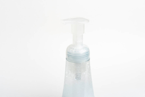 A close-up image of the translucent top pump and bottle of a foam soap plastic dispenser set on a white background. - Foto, afbeelding